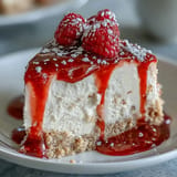 Creamy no-bake cheesecake with buttery crust and glistening fresh raspberry coulis.