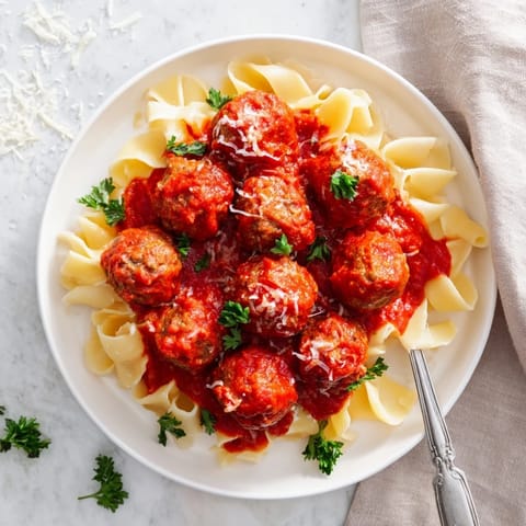 Plump turkey meatballs baked to perfection, resting on a bed of al dente pasta with melted Parmesan cheese.