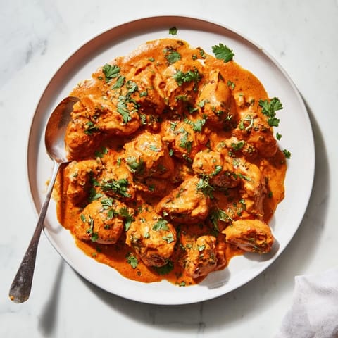 Hearty Chicken Tikka Masala served in a white bowl, ready to be enjoyed with fluffy basmati rice and naan bread.