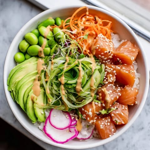 Freshly prepared Poke Bowl featuring diced tuna, edamame, and pickled ginger, drizzled with spicy mayo and sesame seeds.