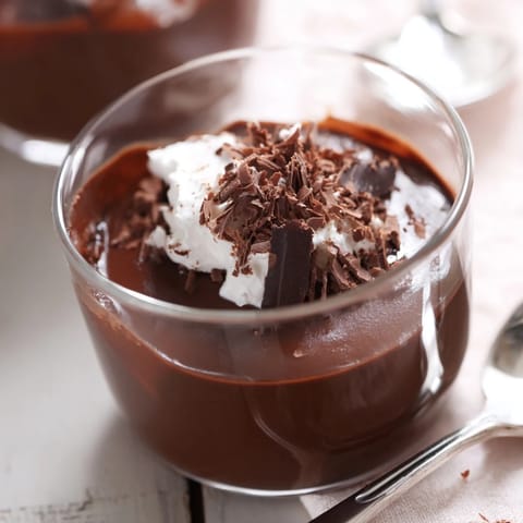 Creamy chocolate pudding in a glass topped with whipped cream and chocolate shavings
