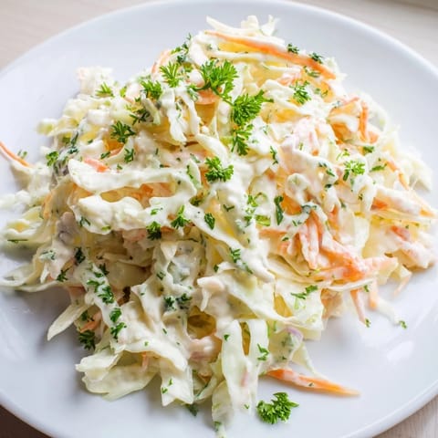 A chilled bowl of Coleslaw with Apple, featuring crisp vegetables and a light yogurt dressing.