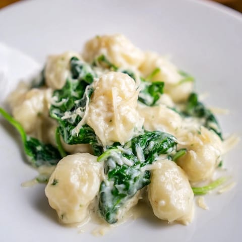A skillet of Creamy Garlic Gnocchi, garnished with extra Parmesan and a crack of black pepper, steam rising invitingly.