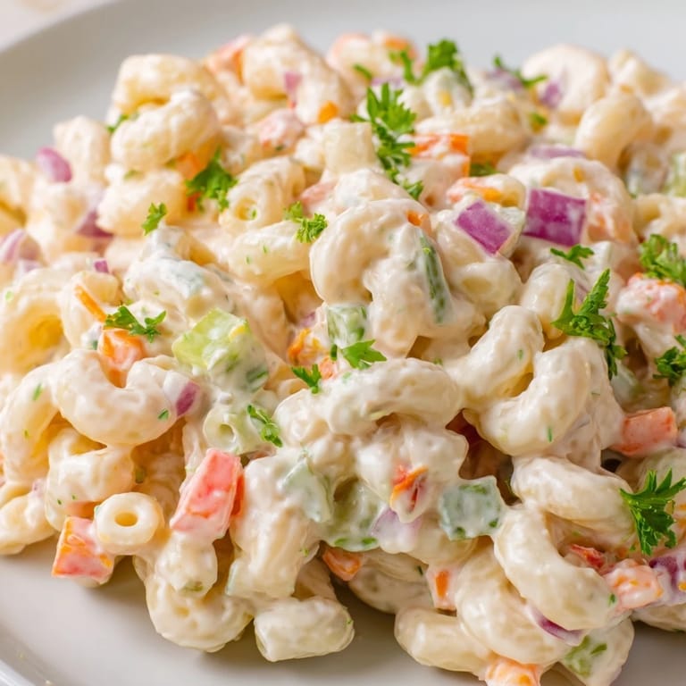 Homemade Macaroni Salad served chilled at a picnic with hard-boiled eggs for added protein.