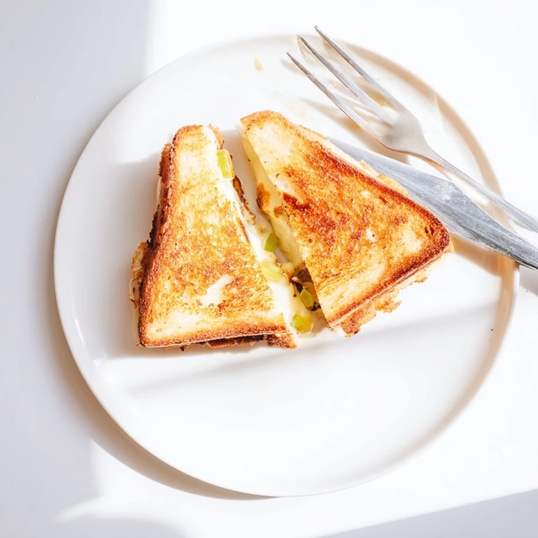 Sliced in half, this Havarti & Caramelized Leek Grilled Cheese reveals a layer of savory, sweet caramelized leeks tucked between Havarti slices.