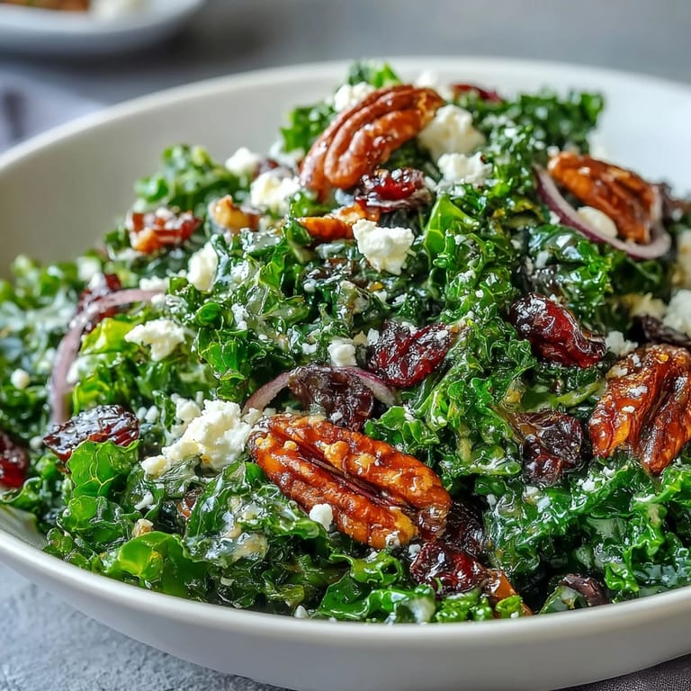 Hearty vegetarian kale salad with tangy maple mustard dressing, red onion slices, and feta cheese crumbles served warm and inviting.