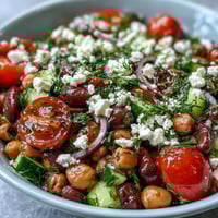 A vibrant bowl of Greek Bean Salad with lemon marinated beans, feta, and fresh herbs on a rustic table.