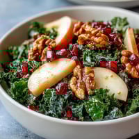 Freshly massaged kale topped with sliced apples, ruby-red pomegranate seeds, and chopped walnuts tossed in a zesty apple cider vinaigrette.