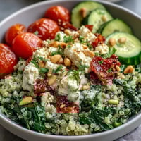 Freshly sautéed spinach and crumbled feta top a warm quinoa base with vibrant cherry tomatoes and crisp cucumber in this Spinach and Feta Grain Bowl.