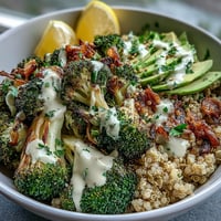 Golden roasted broccoli and red onion over fluffy quinoa, drizzled with creamy tahini sauce and topped with avocado slices.