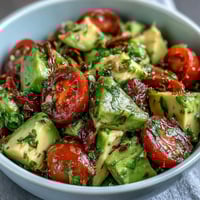 Fresh cucumber tomato avocado salad with lemon dressing, a vibrant mix of crisp vegetables and creamy avocado in a zesty citrus vinaigrette.
